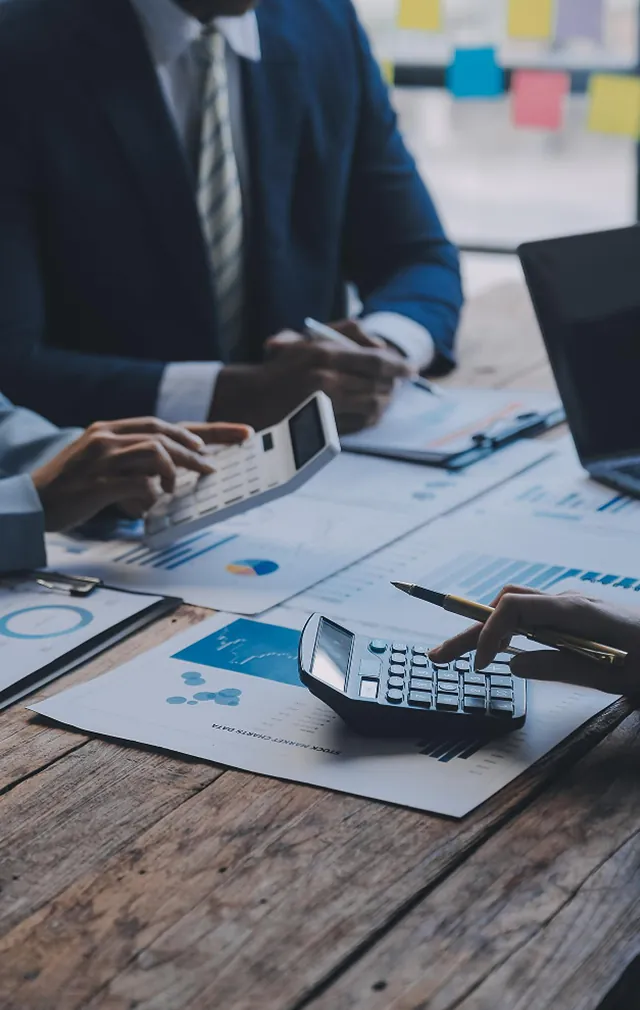 Financial professionals reviewing reports and calculations at a desk